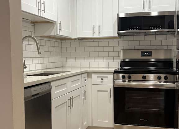A kitchen with white cabinets and a stainless steel counter.