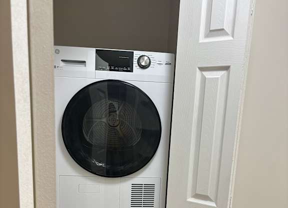 Two front loading washing machines are installed under a cabinet.