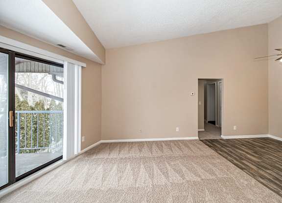 A room with a carpeted floor and a ceiling fan.