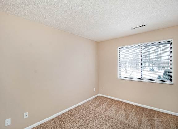 A room with a window and carpeted floor.