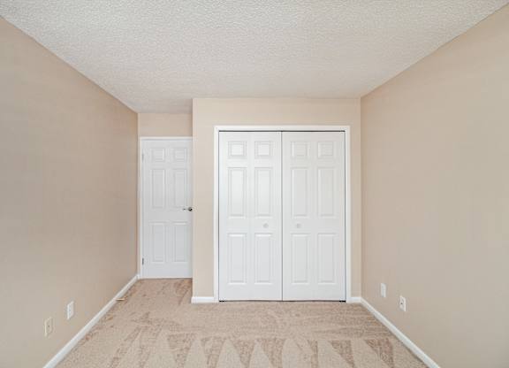 A room with a white closet and carpeting