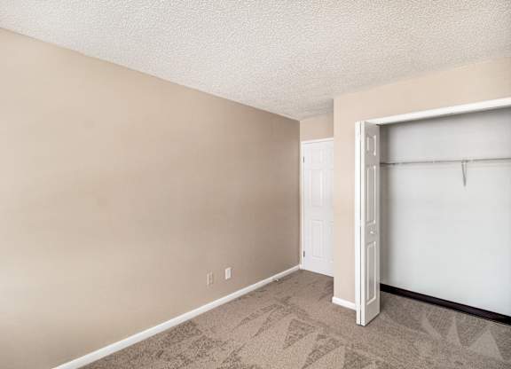 A room with a white door and a carpeted floor.