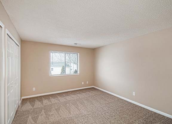 A room with a carpeted floor and a window.