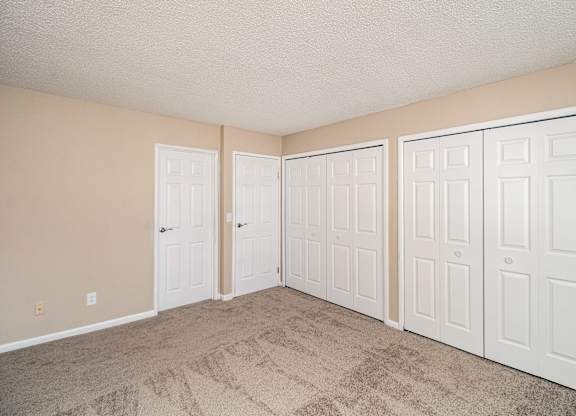 A room with three white doors and beige walls.