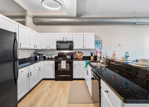 A kitchen with black countertops and white cabinets.