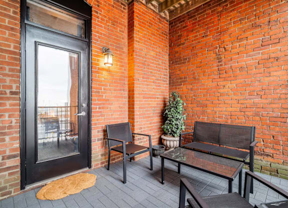 A black door is on the left of a brick wall with a bench and a table in front of it.