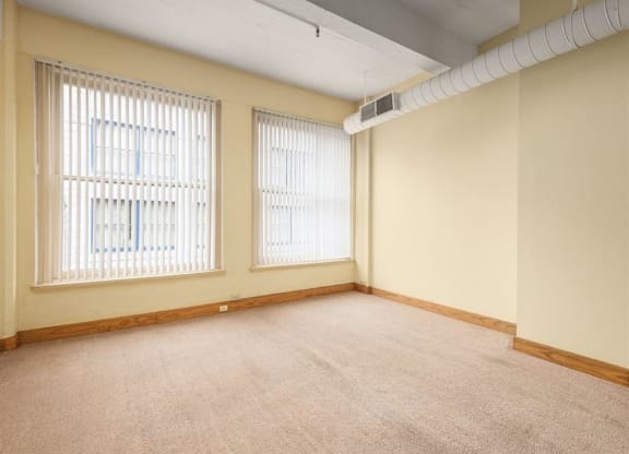 an empty room with three windows and a white pipe
