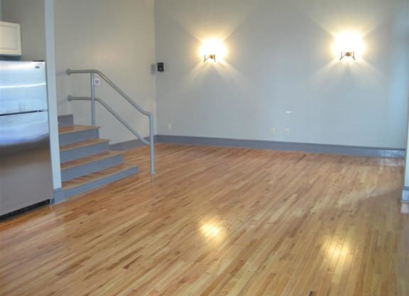 a large room with a wooden floor and stairs at East 4th Street, Cleveland, Ohio