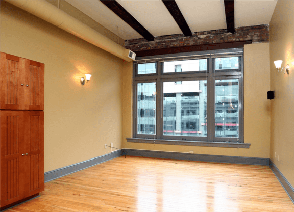 an empty room with a large window and wooden floors