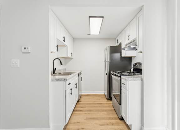 A white kitchen with a black fridge and stove.