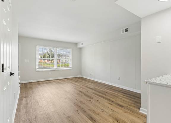 A room with wooden flooring and white walls.