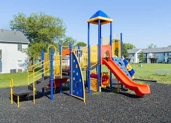A playground with a blue and yellow structure and a red slide.