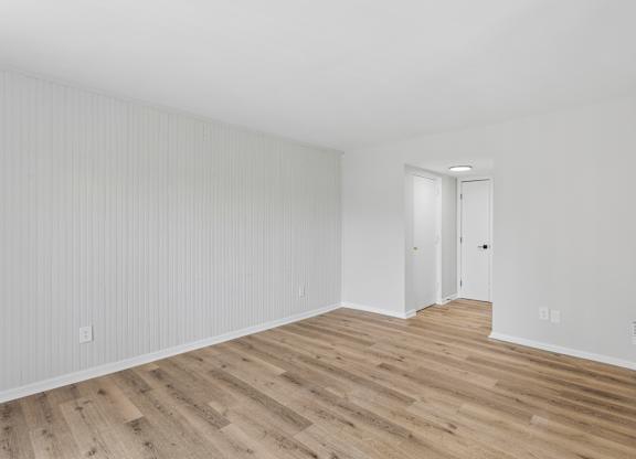 A room with wooden flooring and white walls.