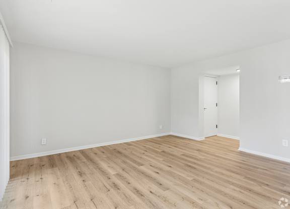 A room with wooden flooring and white walls.