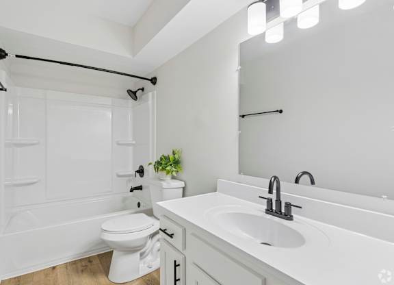 A white bathroom with a toilet, sink, and mirror.