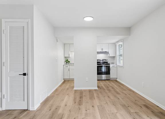 A kitchen with white walls and wooden floors.