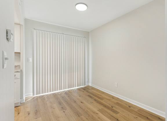 A room with wooden flooring and white walls.