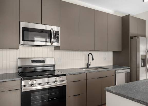 A modern kitchen with a stainless steel oven and brown cabinets at The Park Apartments, Cleveland 44113