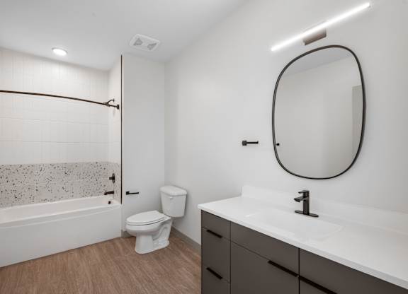A bathroom with a white sink, toilet, and a bathtub with a shower curtain at The Park Apartments, Cleveland , OH, 44113