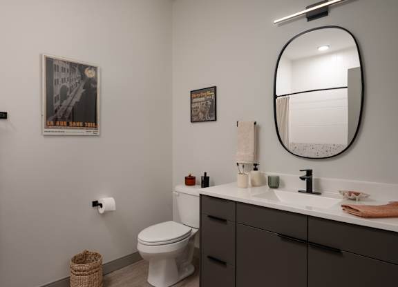 A bathroom with a toilet, sink, and a poster on the wall at The Park Apartments, Cleveland 44113