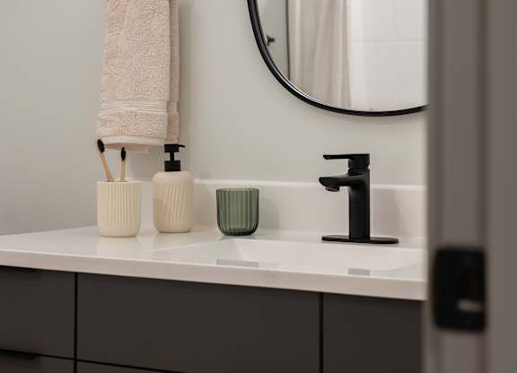 A bathroom with a white sink and a round mirror at The Park Apartments, Cleveland , OH, 44113
