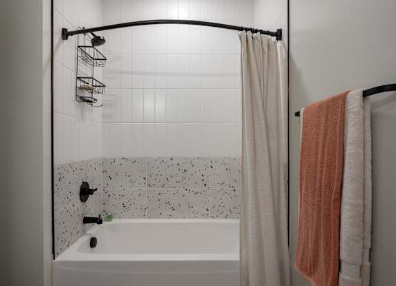 A white bathtub with a shower curtain and a towel hanging on a rack at The Park Apartments, Cleveland , OH, 44113