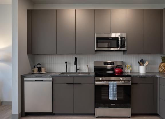 A modern kitchen with a stove top oven and a microwave above the sink at The Park Apartments, Cleveland , Ohio