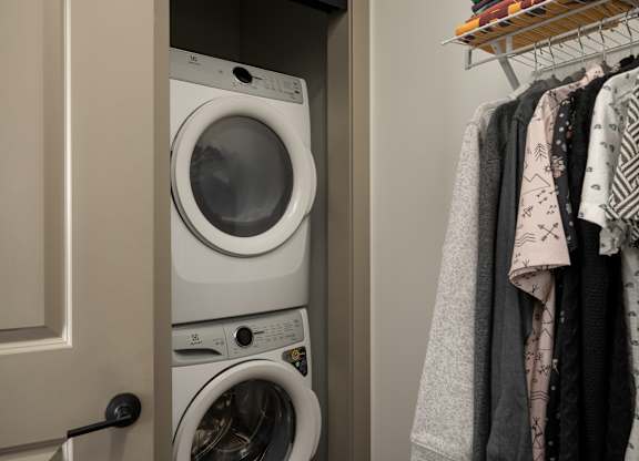 A white washing machine is in a cabinet under a white door at The Park Apartments, Cleveland