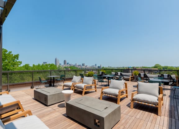 an outdoor deck with lounge chairs and fire pits with a view of the Cleveland skyline at TREO Apartments, Cleveland, 44116