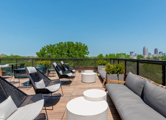 a rooftop deck with couches and chairs and a view of the Cleveland skyline at TREO Apartments, Cleveland, 44116