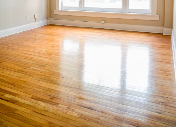 an empty living room with wood floors and a large window