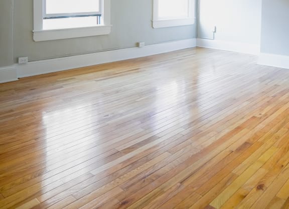 an empty room with a wood floor and two windows