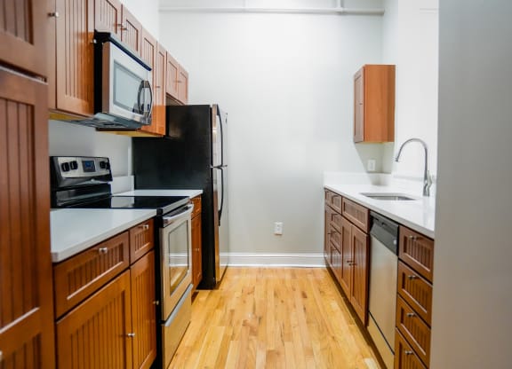 a kitchen with wood floors and wooden cabinets and a black refrigerator at East 4th Street, Cleveland, Ohio