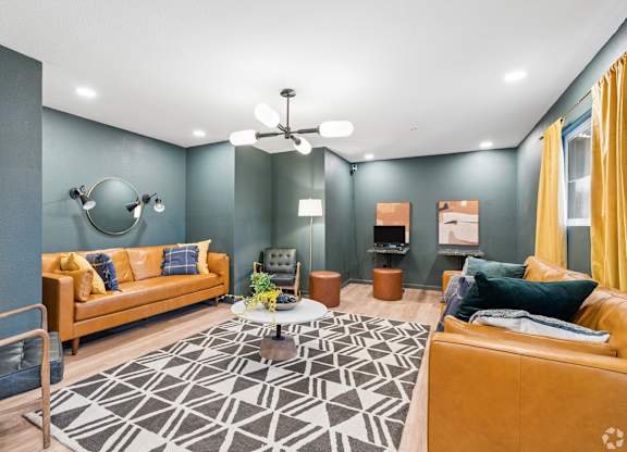 A living room with a yellow couch and a black and white rug.