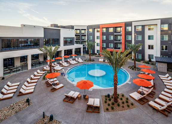 A pool surrounded by sun loungers and umbrellas.