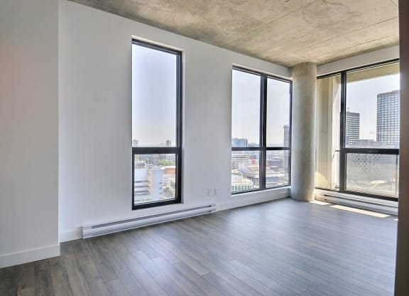 an empty living room with large windows and a city view