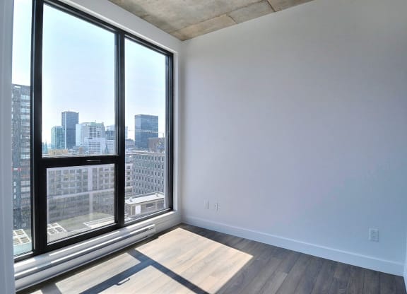 an empty living room with large windows and a city view