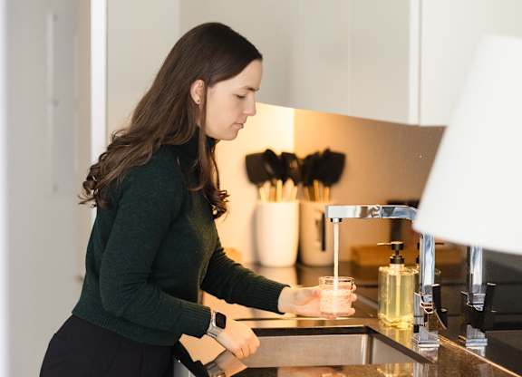 A woman is washing dishes in a modern kitchen.