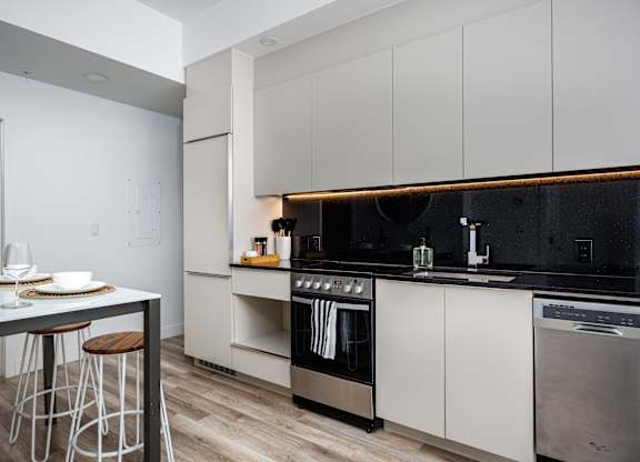 A modern kitchen with a black countertop and stainless steel appliances.