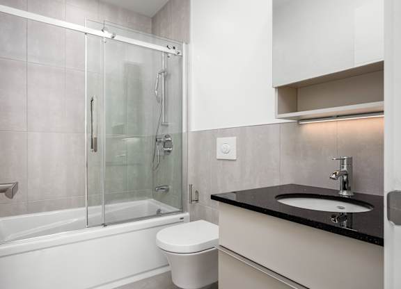 A modern bathroom with a white toilet and a black countertop.