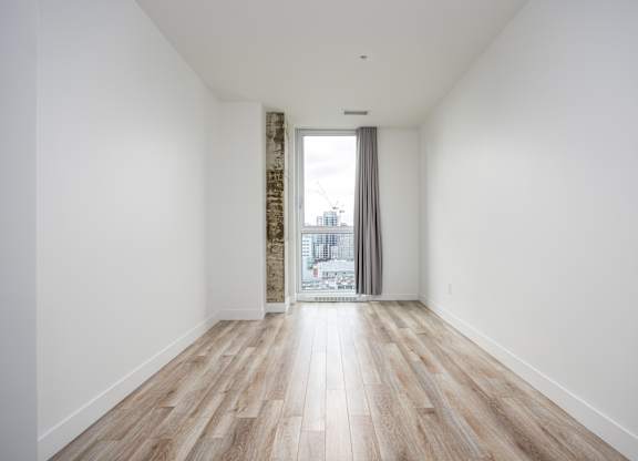 A room with a window and wooden flooring.