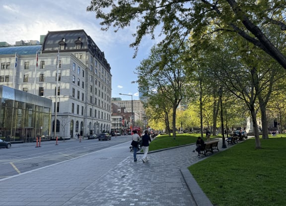 people walking down a sidewalk in a park in front of a building
