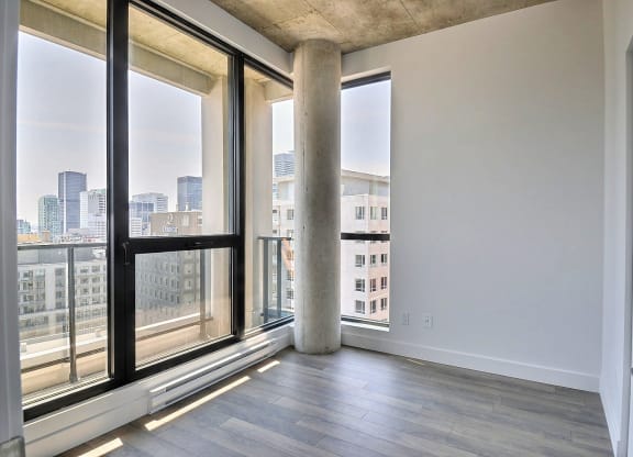 an empty living room with large windows and a city view
