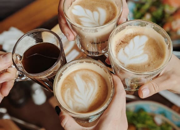 a group of people holding up cups of coffee