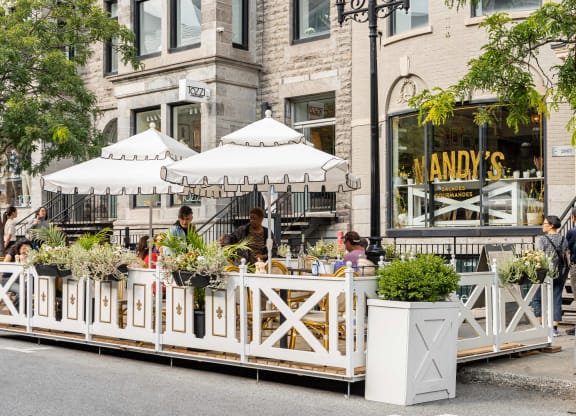 people sitting at a table at a restaurant on a street