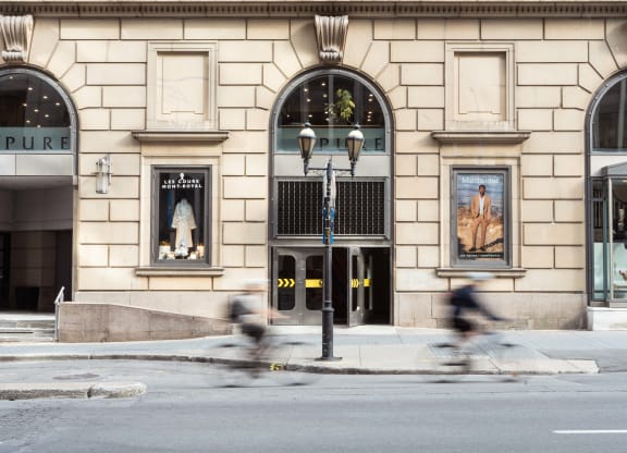 two people biking down a city street in front of a building