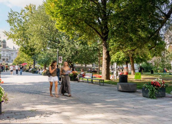 two women standing on a sidewalk in a park