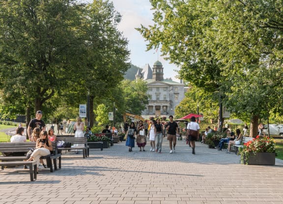 people walking and sitting on benches in a park