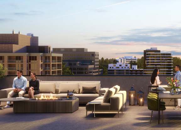 A group of people are sitting on a rooftop patio with a view of the city.