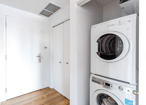 a washer and dryer in a laundry room with white walls and wood floors